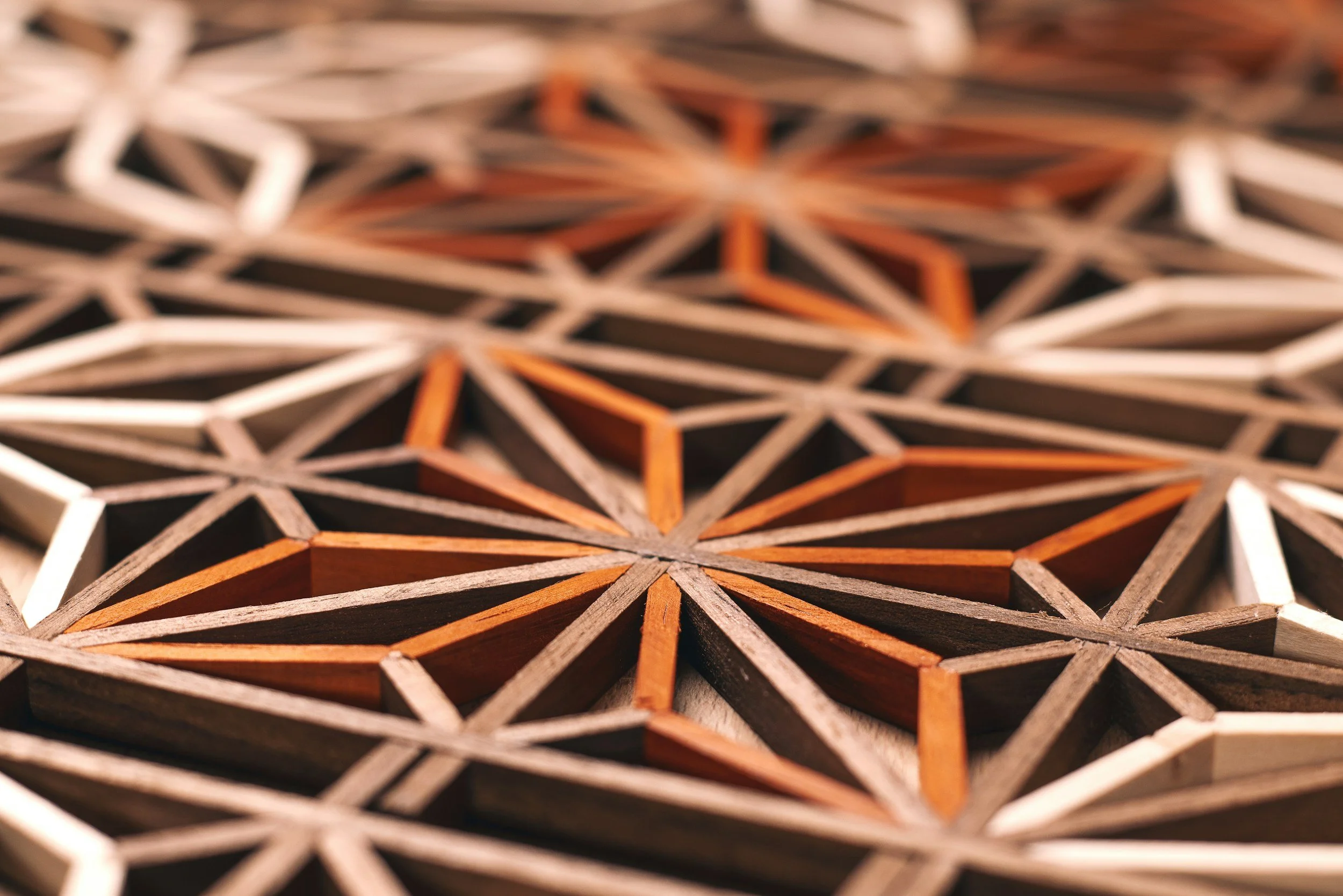 Close-up view of a geometric wooden lattice pattern with a dark background.