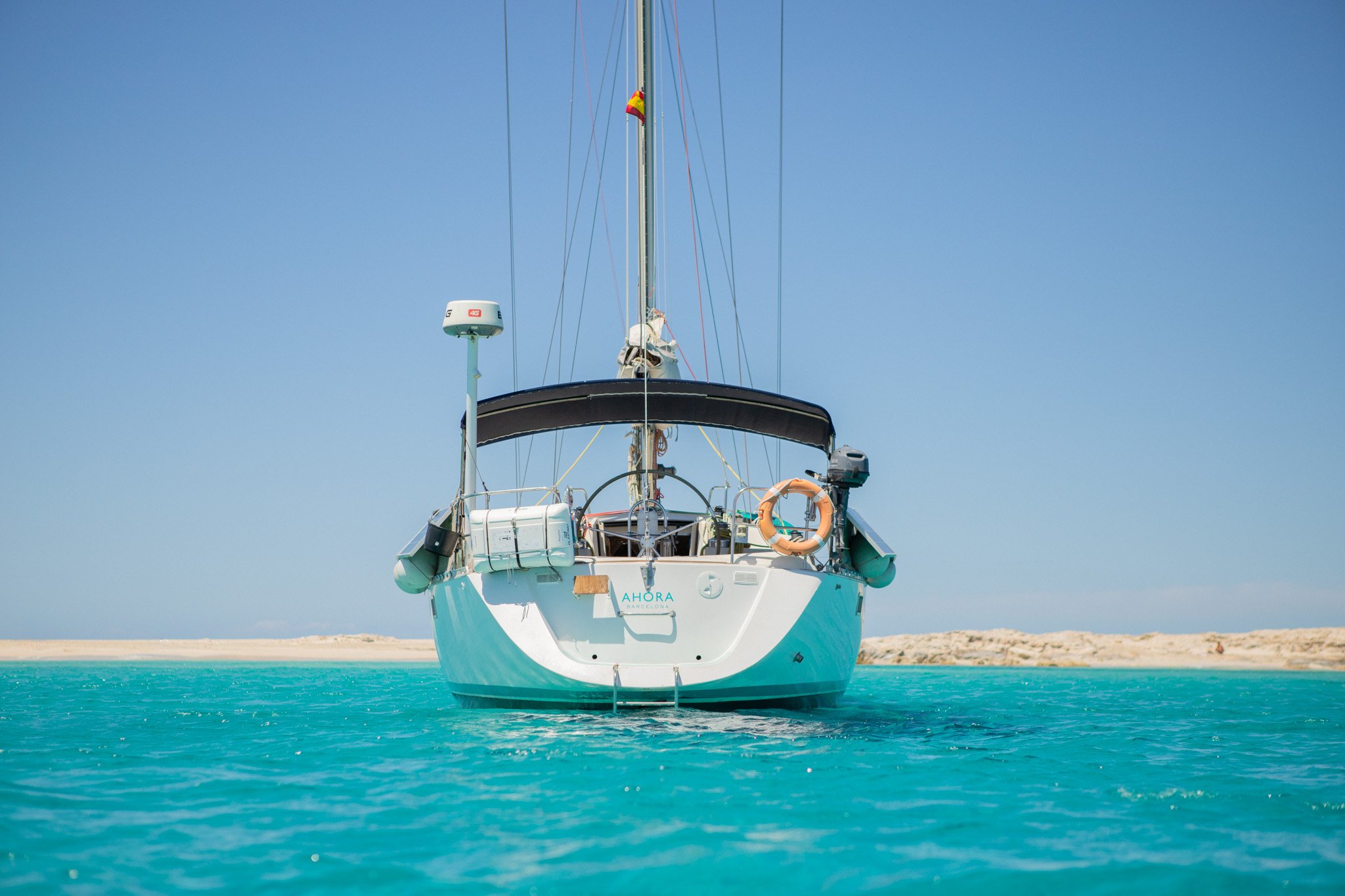 A white yacht anchored in turquoise water with a clear blue sky in the background.