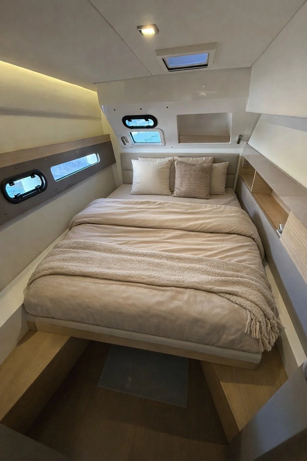 Interior of a small, modern bedroom with a bed, multiple small windows, and wooden shelves in a compact space.
