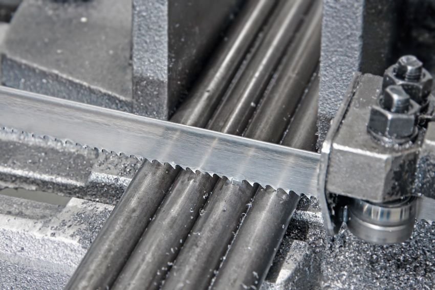 Close-up of a metal saw cutting through a metal piece on a machine.