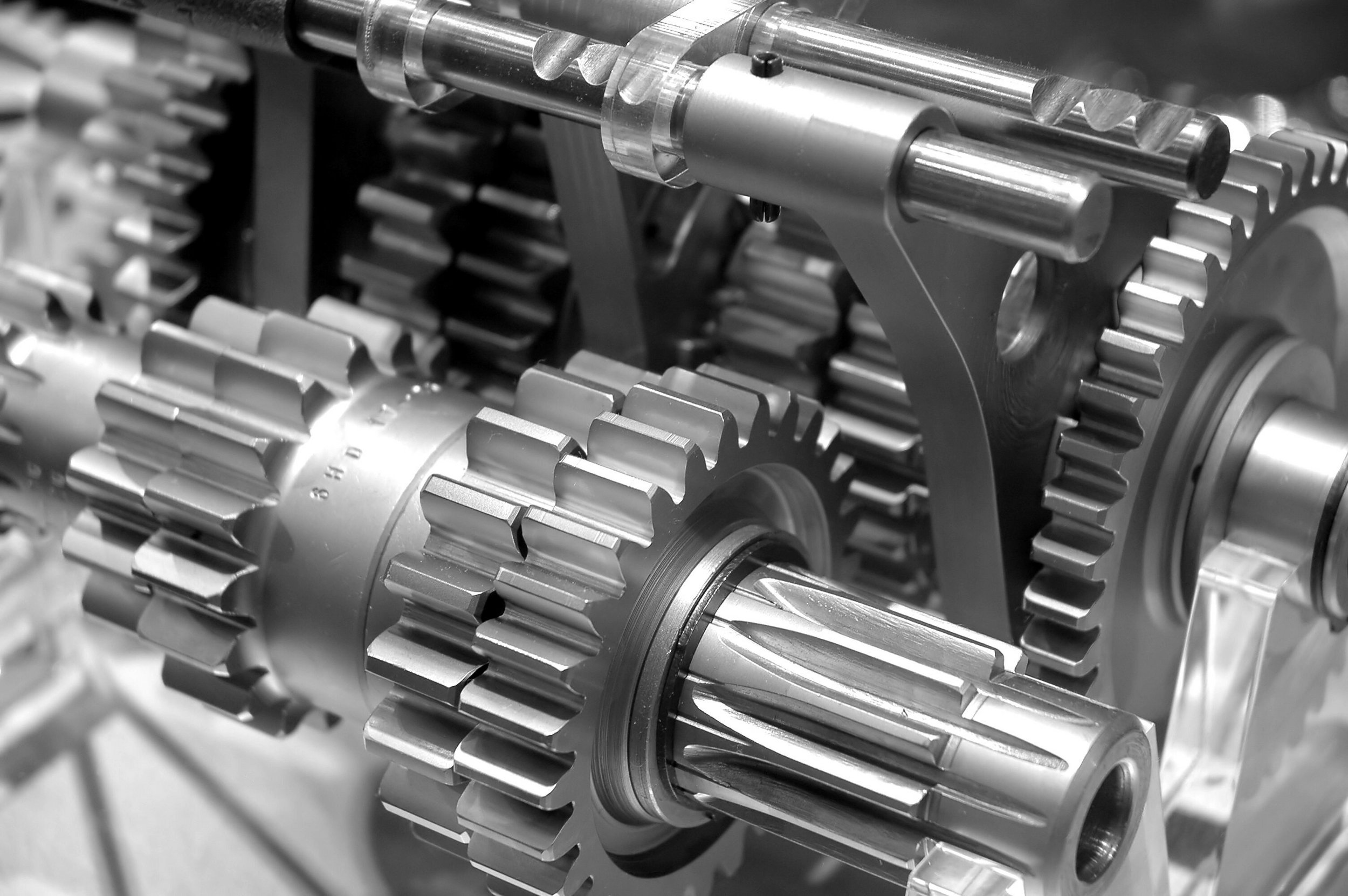Close-up view of metallic gears and shafts, likely part of a machine or gearbox, with visible teeth and detailed machined surfaces.
