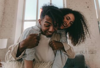 A joyful African American couple smiling and playing together indoors.
