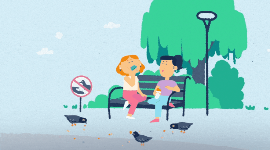 Two women sitting on a park bench, one appears to be sick or crying while the other comforts her. There are four birds on the ground and a no smoking sign nearby. The background includes trees, bushes, and a lamppost.