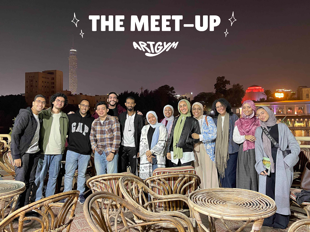 Group of people smiling and posing for a photo on a rooftop at night, with city lights and buildings in the background, including a tall tower.