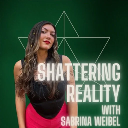 A woman with wavy hair wearing a black top and red pants standing in front of a green background with geometric designs, with text overlay that reads 'Shattering Reality with Sabrina Weibel.'