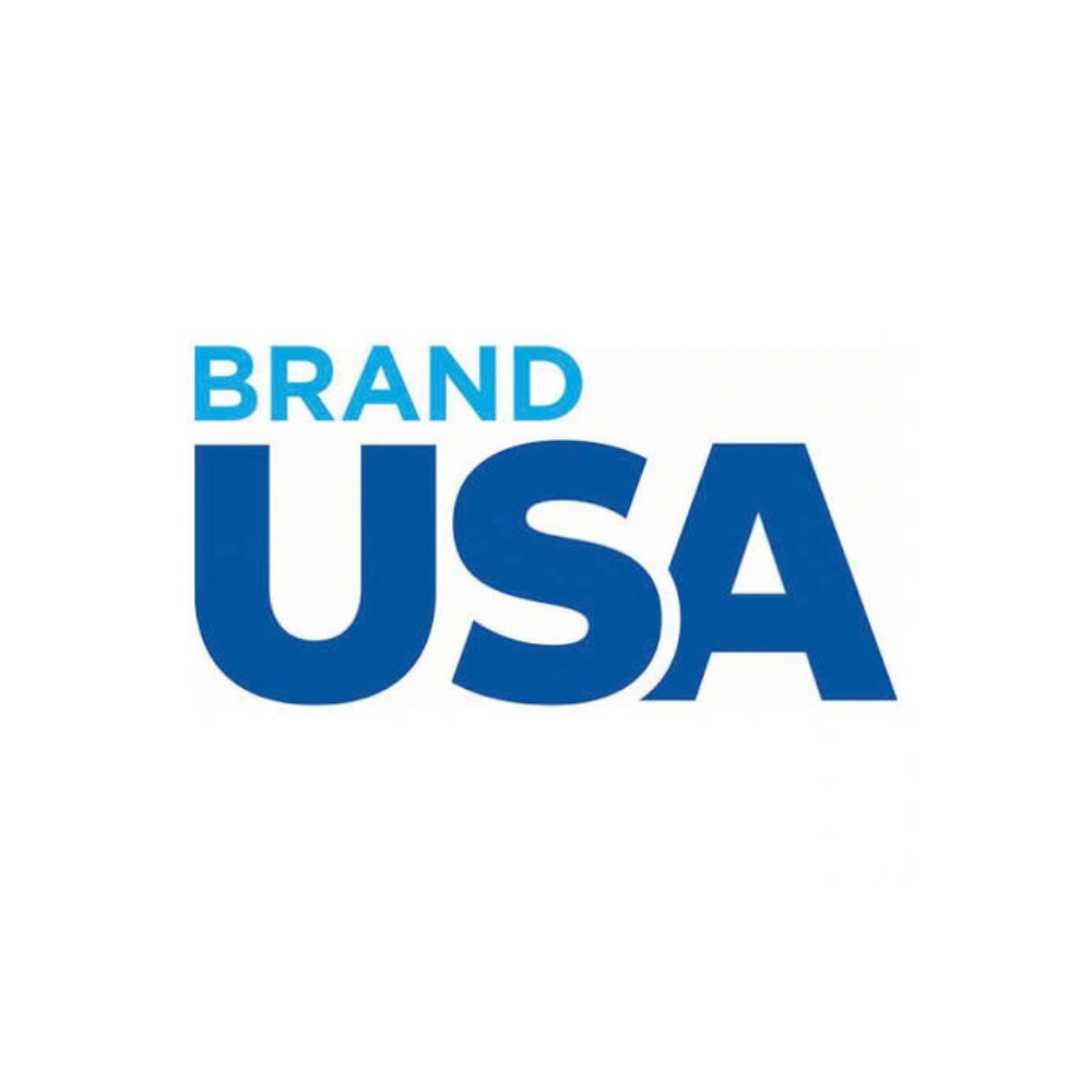 Text reads 'BRAND USA' with 'BRAND' in light blue and 'USA' in dark blue on a white background.