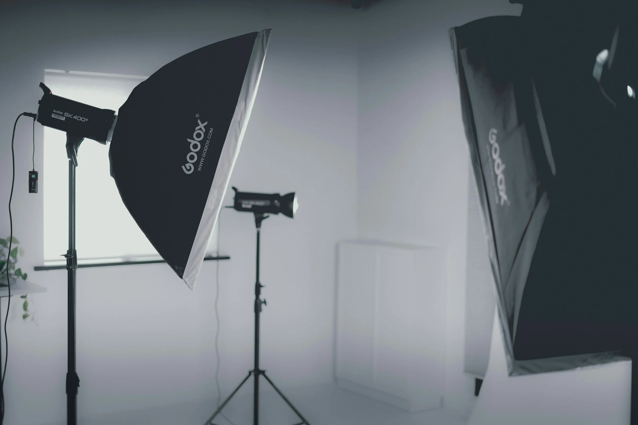 Photography studio setup with softbox lights, a large reflector, and studio equipment.