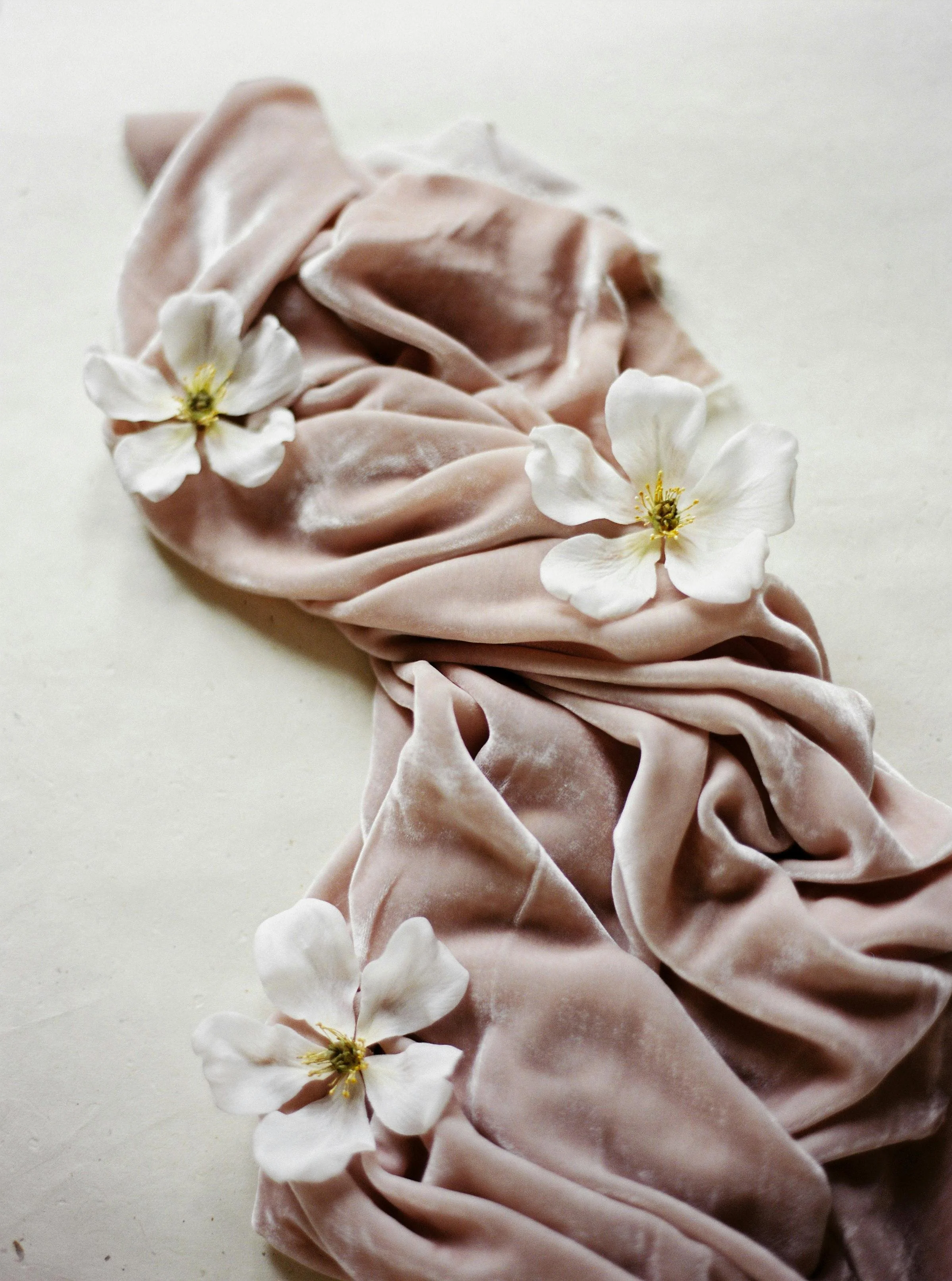 A pink satin scrunchie decorated with small white flowers.