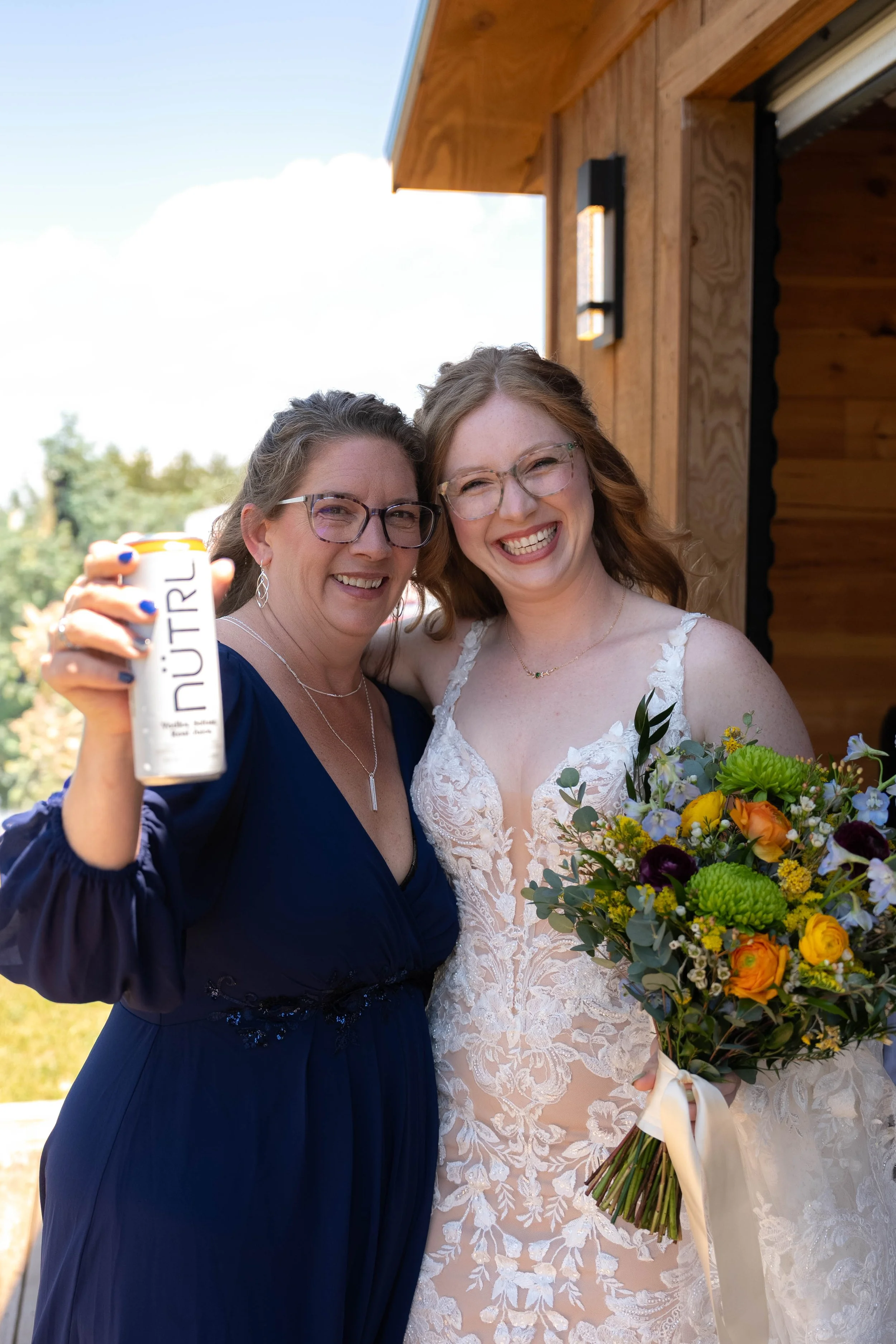 A woman in a dark blue dress holding a beverage with 