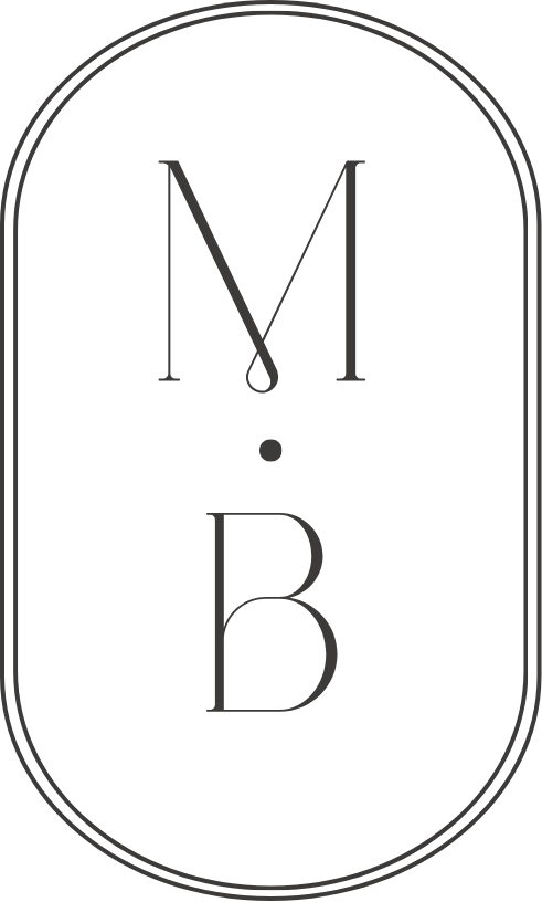 Logo with the letters 'N', 'M', and 'B' arranged vertically and separated by a small dot, enclosed in a double-line oval border.