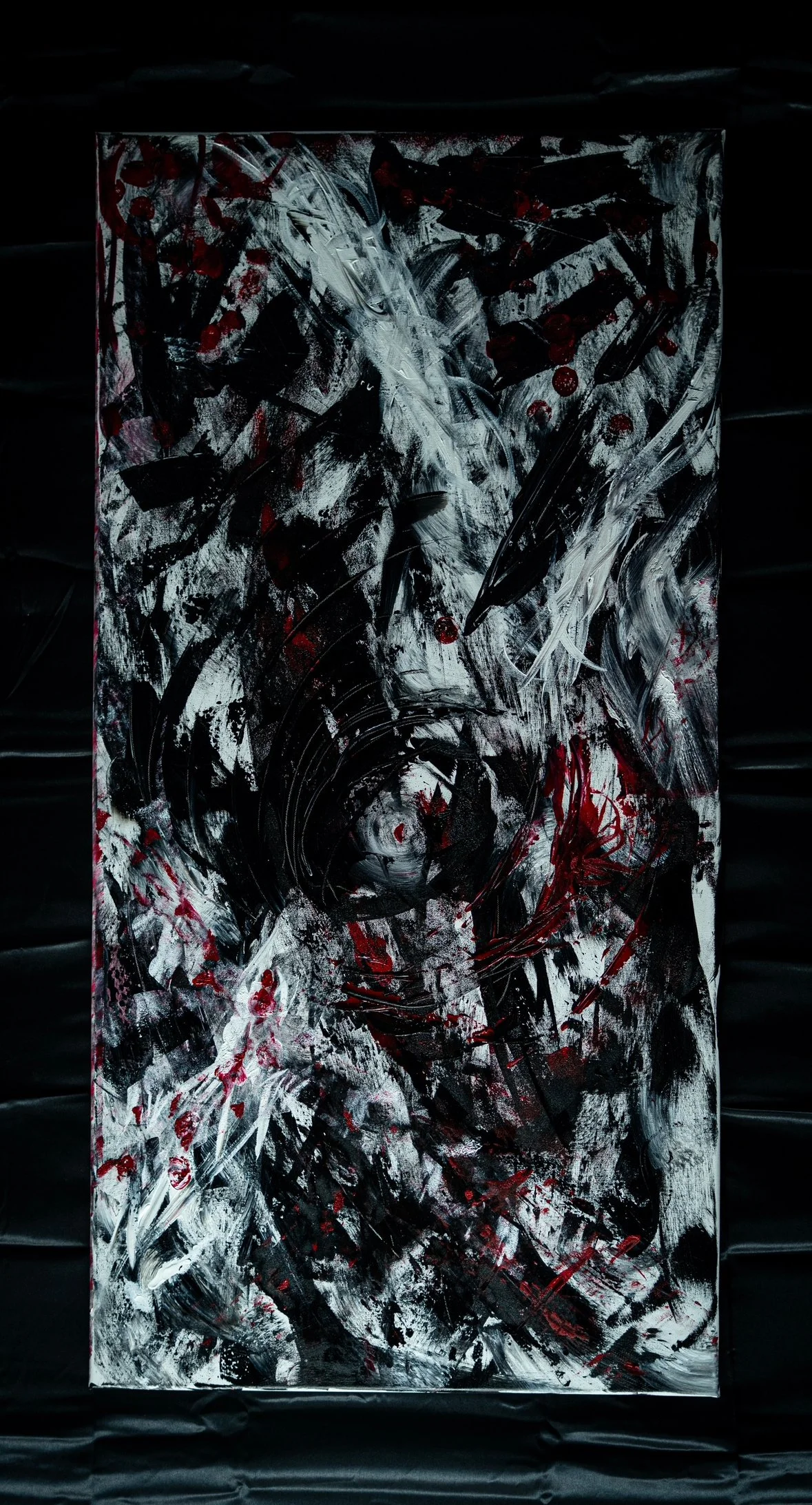 Abstract painting with black, white, and red splashes and strokes on a vertical canvas.