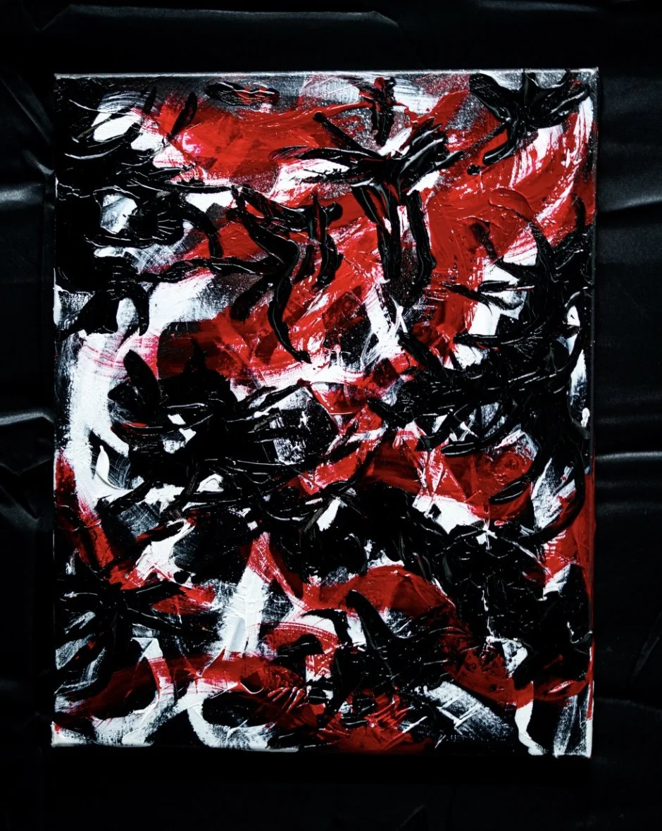 Abstract painting with red, black, and white brushstrokes on a canvas.