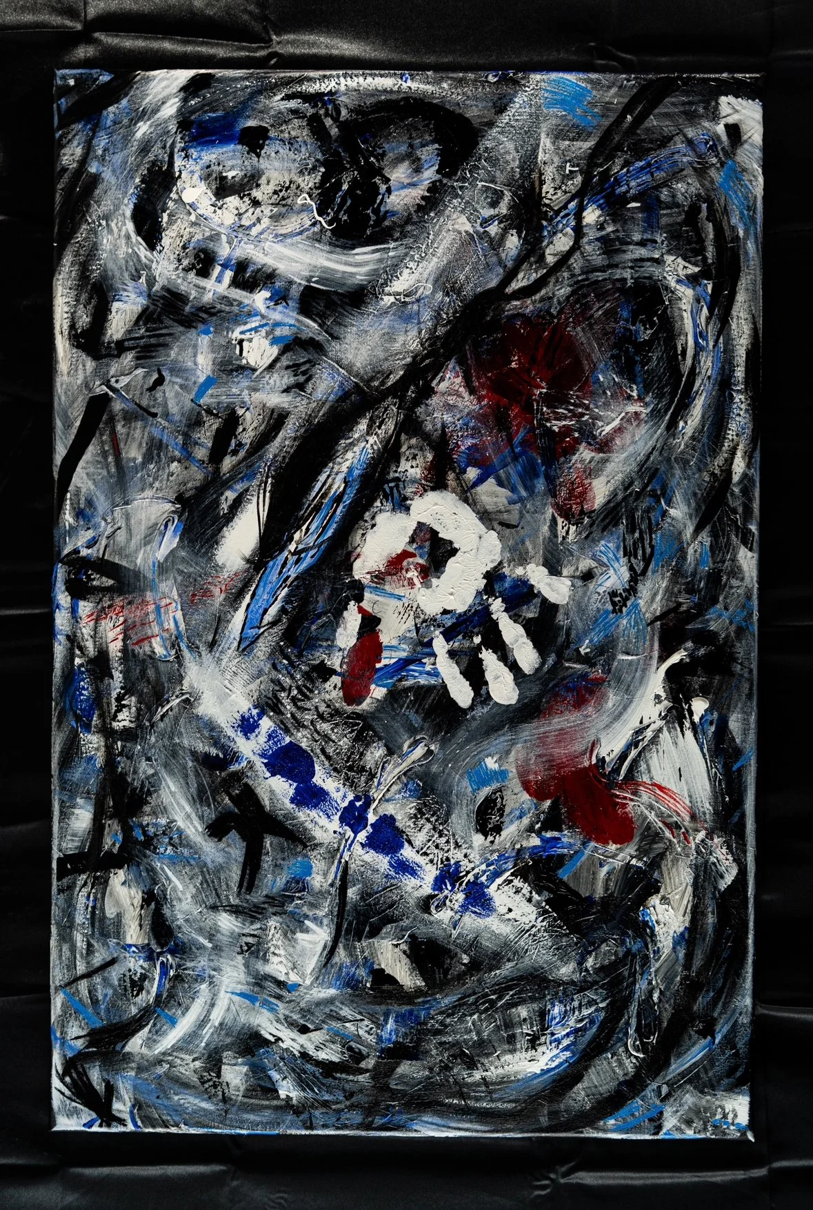Abstract painting with black, white, red, and blue colors, featuring a white handprint near the center.