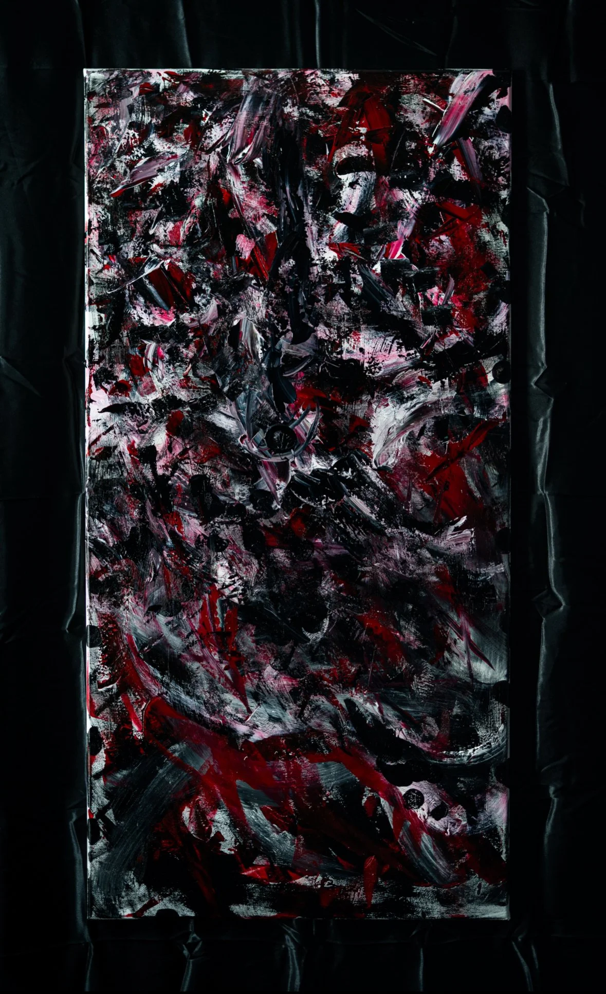 Abstract painting with black, red, and white brushstrokes on a rectangular surface, framed with black fabric.