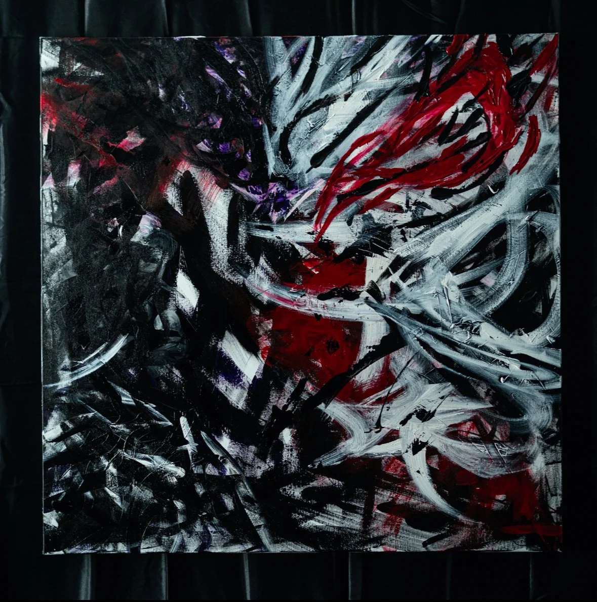 Abstract painting with black, white, red, and purple brushstrokes on canvas.