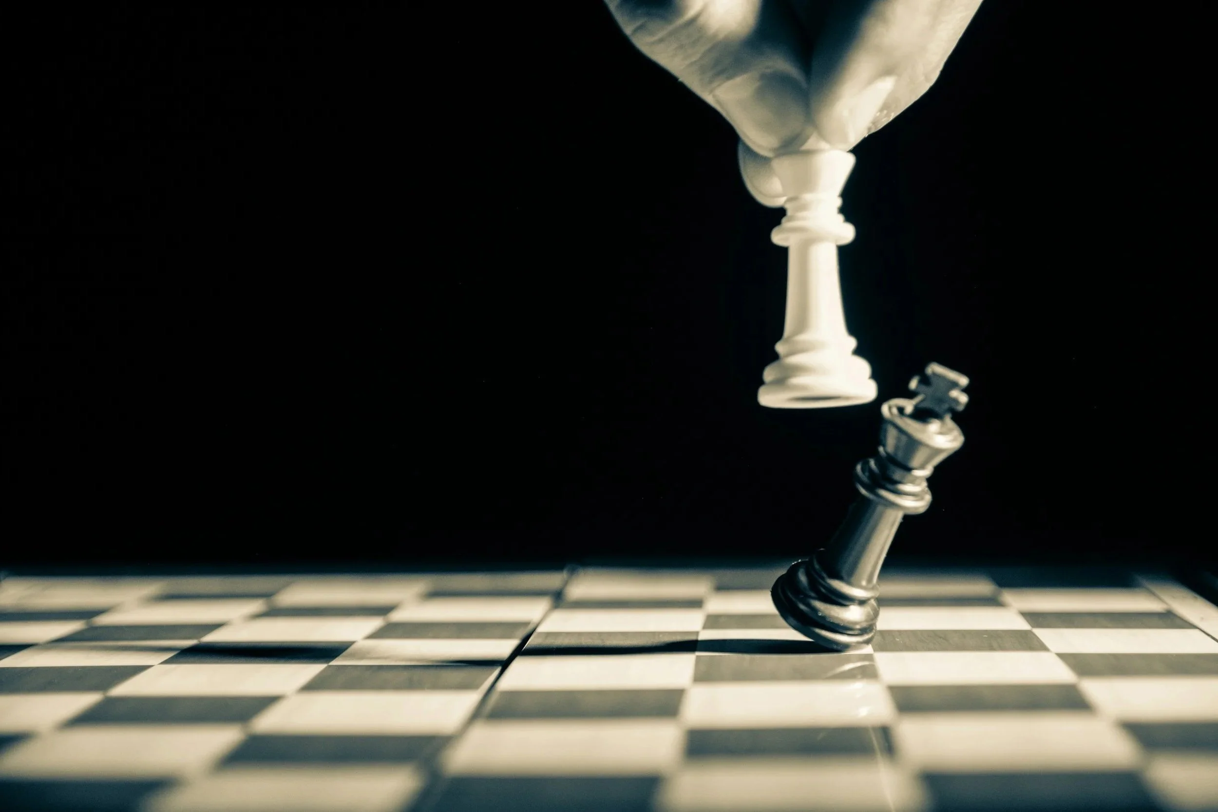A close-up of a white king chess piece falling onto a black and white checkered chessboard.