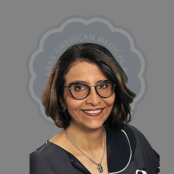 Smiling woman with glasses, wearing a black uniform with white piping, in front of a logo with the text "Arab American Medical".