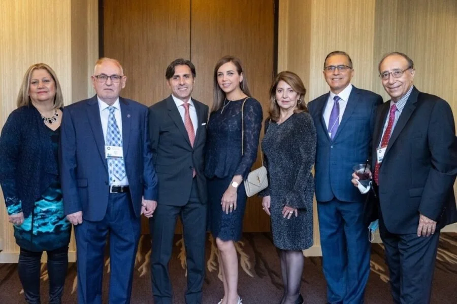 Seven professionally dressed people standing together at an indoor event, posing for a group photo.
