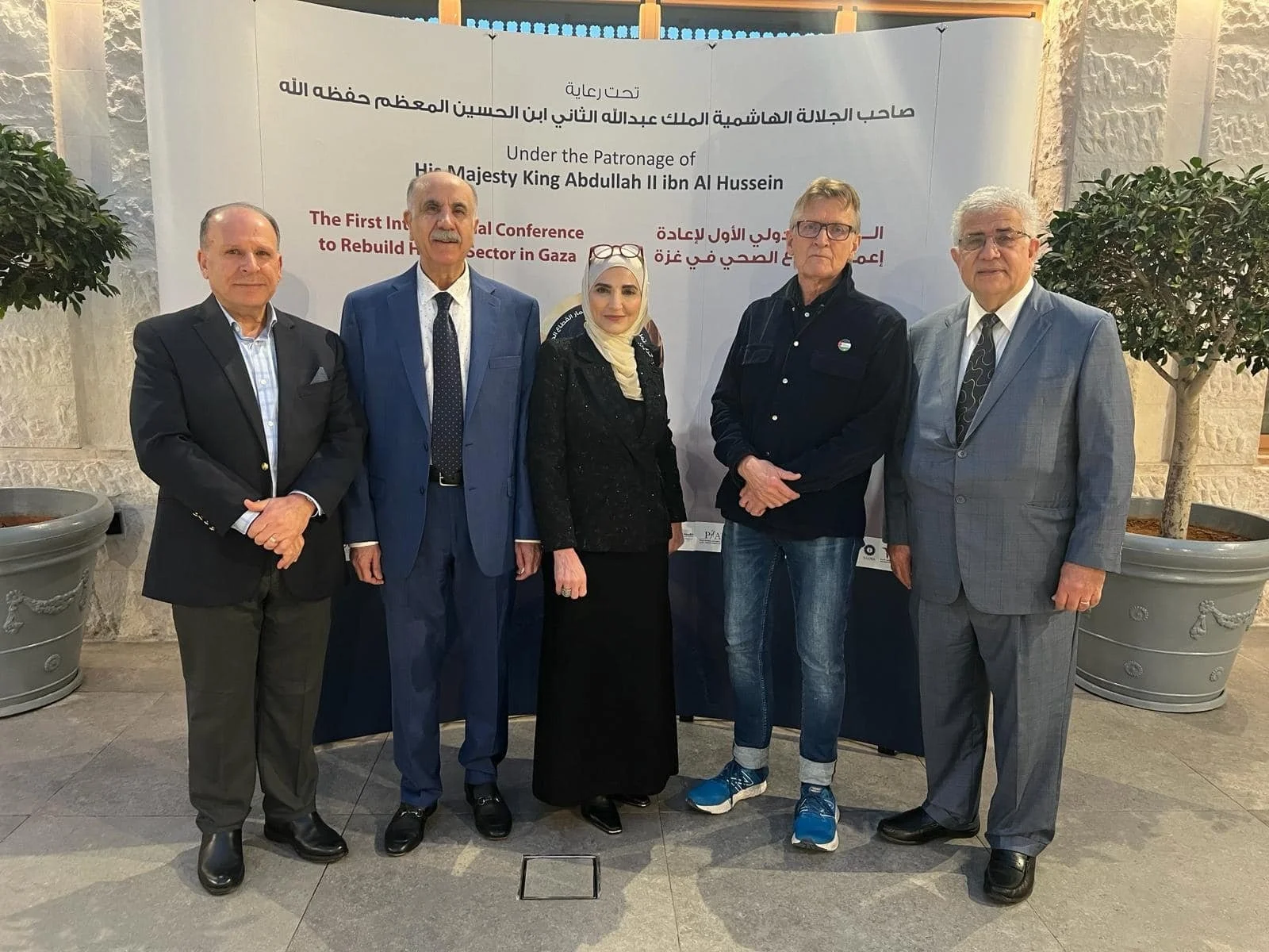 Group of five individuals standing in front of a conference banner, posing for a photo.