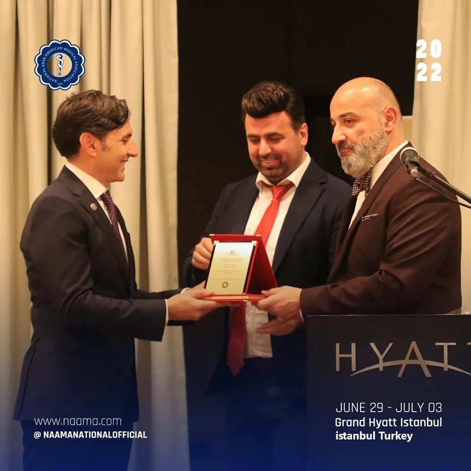 Three men in suits participating in an award ceremony at a Hyatt hotel in Istanbul, Turkey, with the timing June 29 - July 03, 2022, and the event related to the American Medical Association.