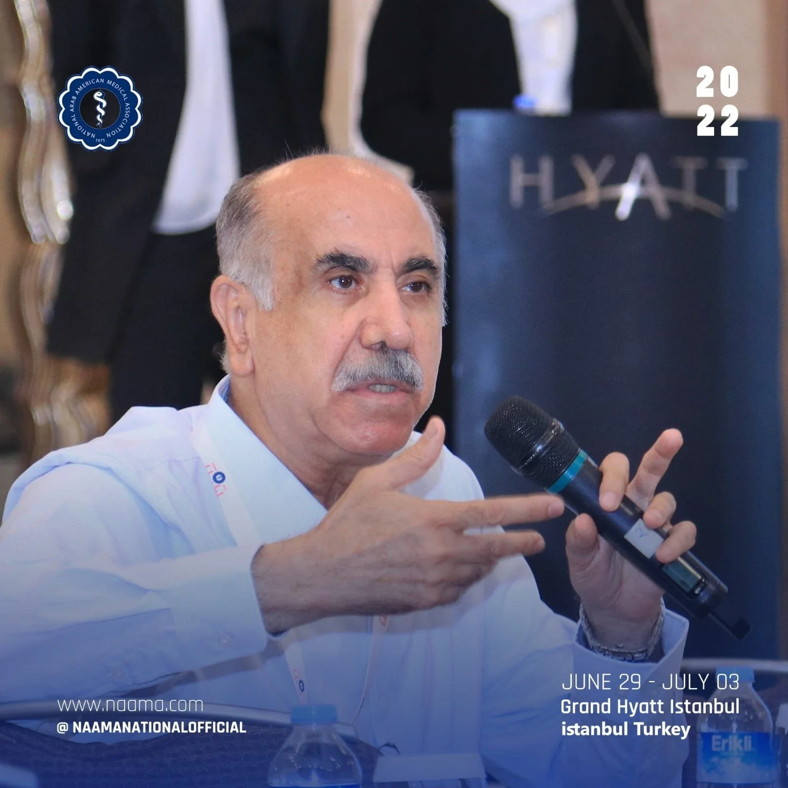 A man with gray hair and a mustache speaking into a microphone at a conference, with text indicating the event is held from June 29 to July 3 at the Grand Hyatt Istanbul, Turkey, organized by the National Arab American Medical Association in 2022.