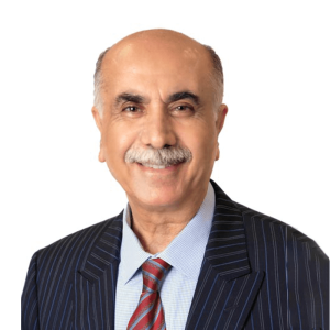 Portrait of a smiling elderly man with a mustache, wearing a dark pinstripe suit, light blue shirt, and red tie, against a white background.