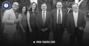 Group of seven people in formal attire standing outdoors with trees in the background.