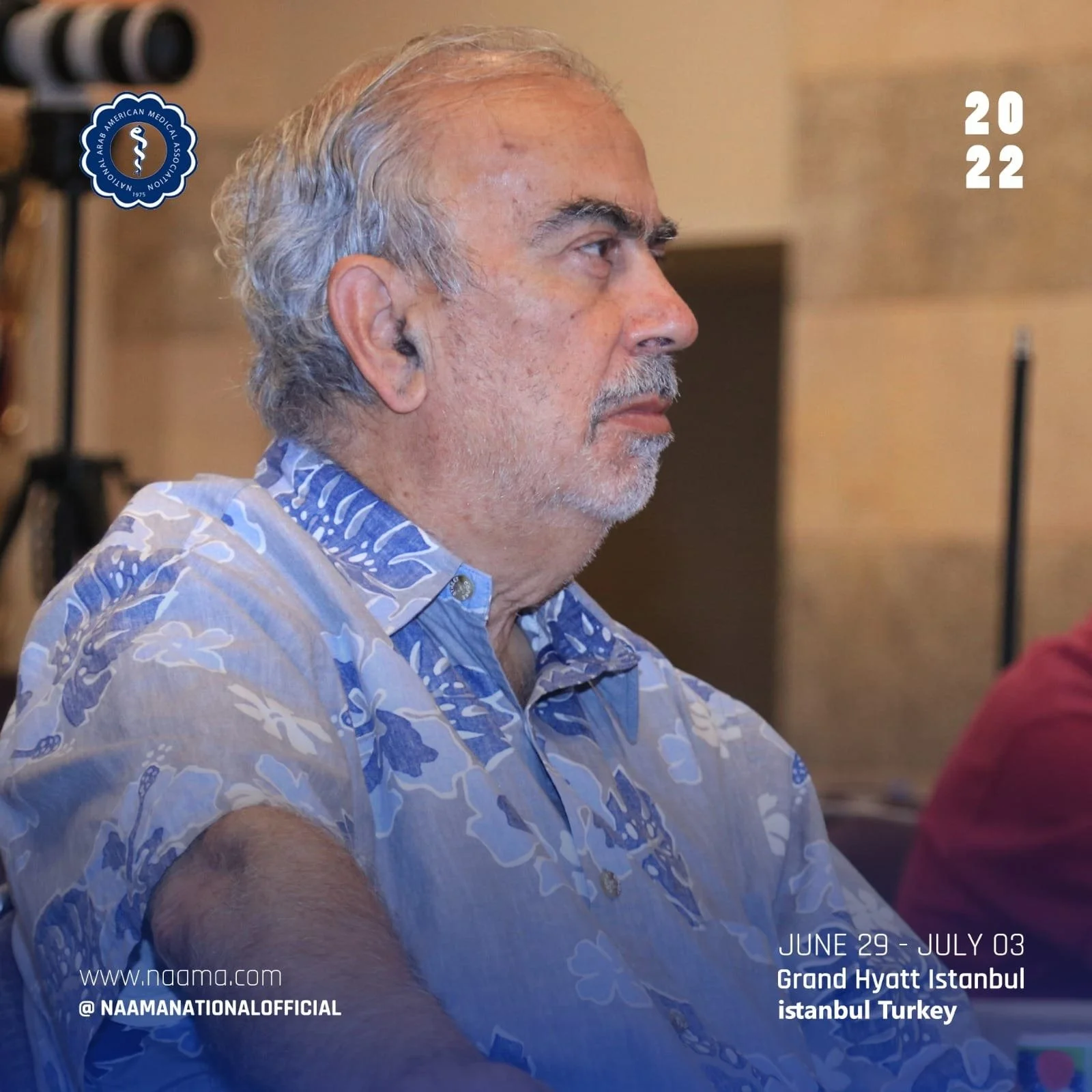 Profile of an elderly man with gray hair and a beard, wearing a blue and white patterned shirt, attending an event at Grand Hyatt Istanbul in Turkey, during the NAAM National Official event held from June 29 to July 03, 2022.