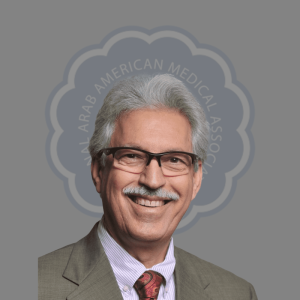 Portrait of a smiling man with gray hair, glasses, and a suit in front of a logo for the Arab American Medical Association.