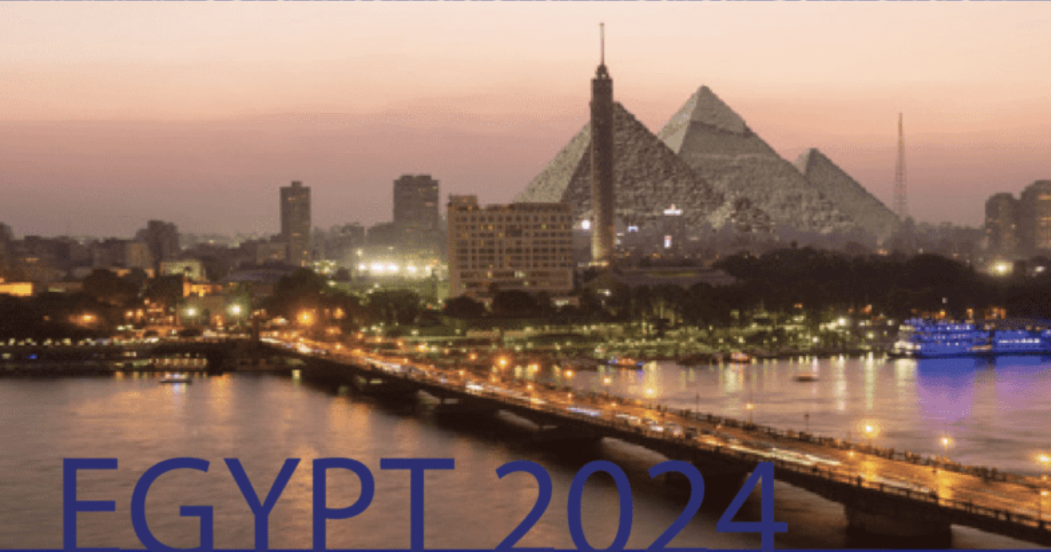 Twilight view of Cairo, Egypt, with the Pyramids of Giza in the background and city lights along the riverfront.