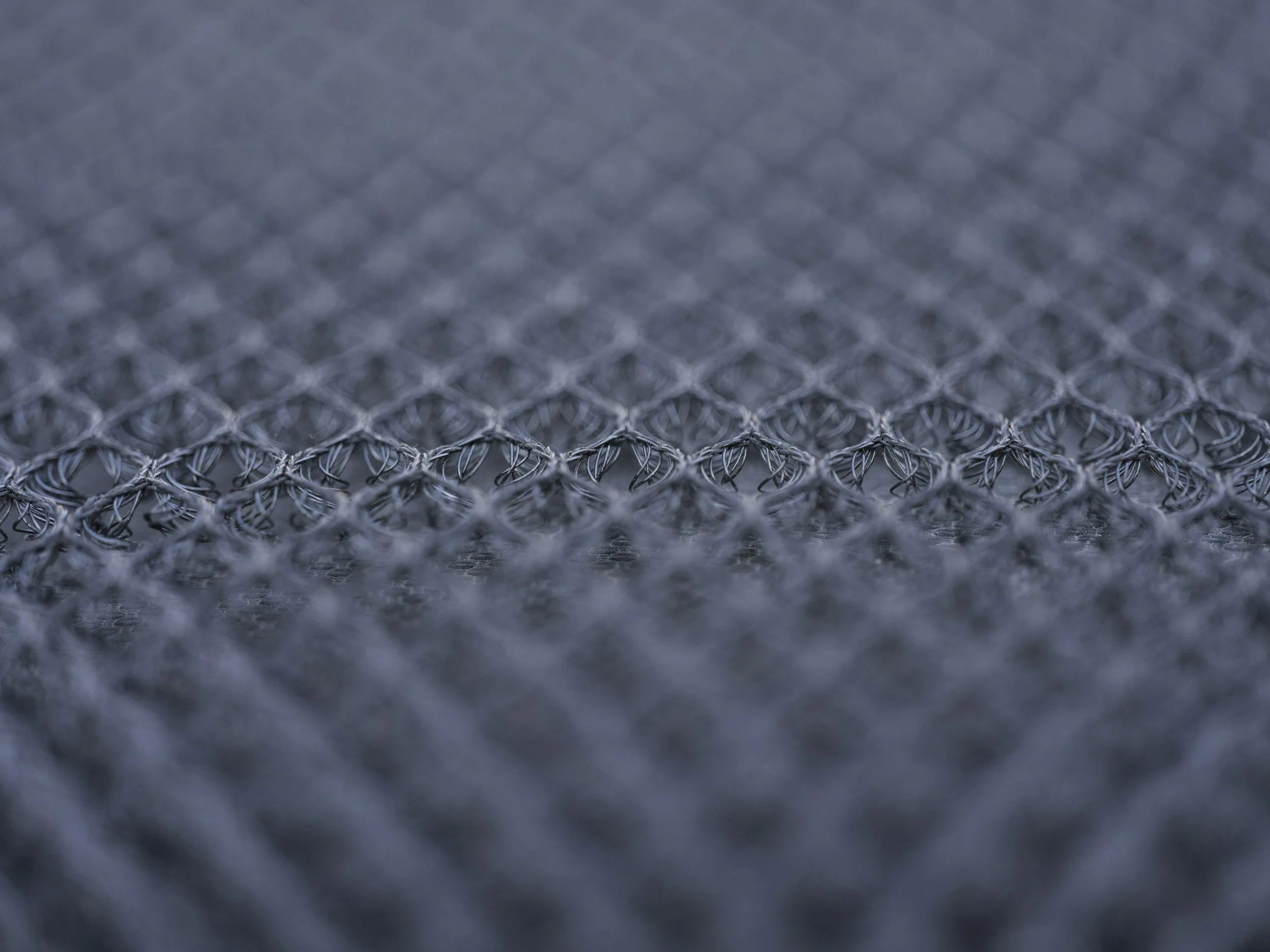 Close-up of a metallic chain-link fence with a grid pattern.