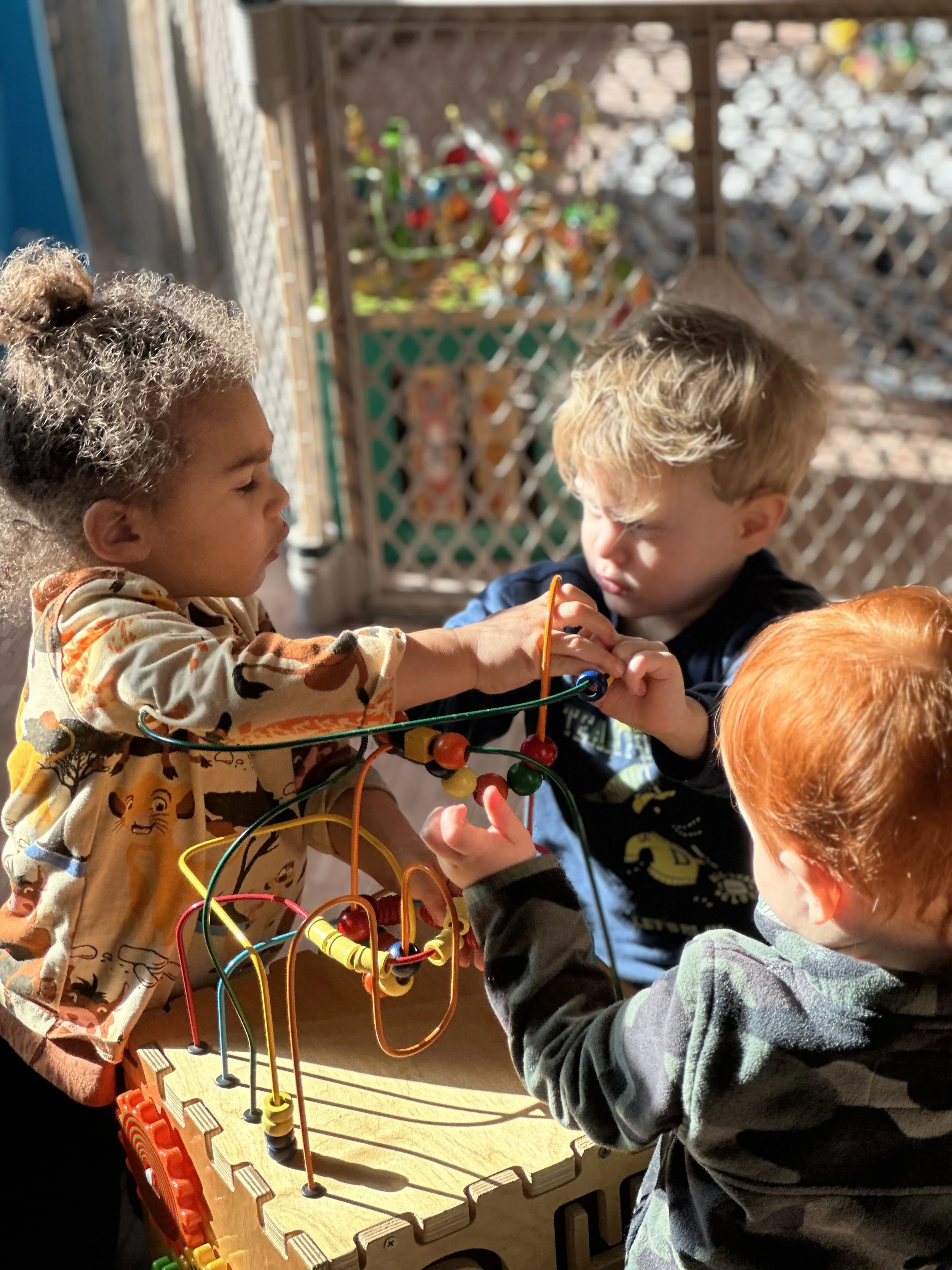 three young toddlers playing with an activity cube inside Bloom Waldessori Play Space located in Stroudsburg, PA