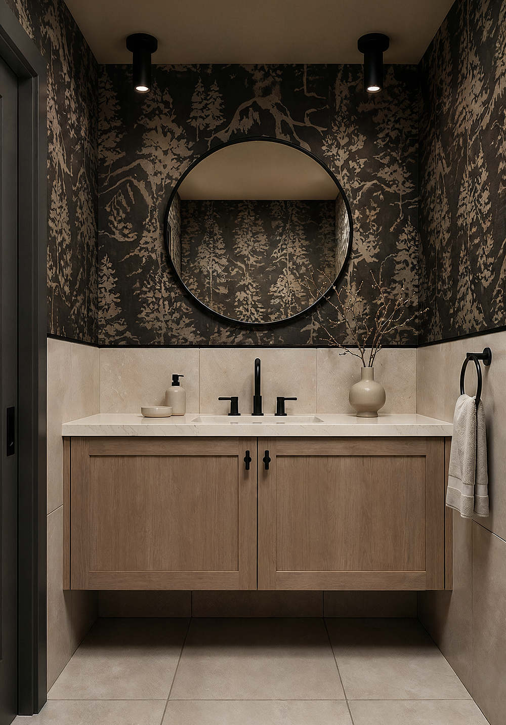 Powder room at Wren with a black and antique gold forest wallcovering over a stone look wainscot, a floating white oak vanity, a round black mirror, and black cylinder ceiling lights.