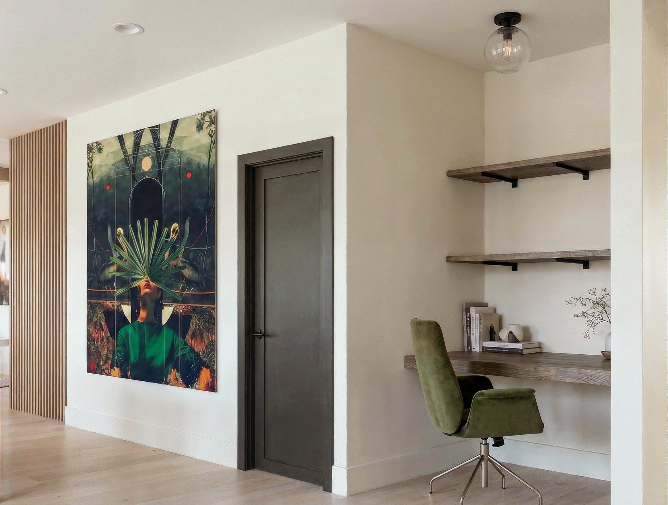 A built-in desk nook in the Wyandot duplex, with a floating wood desk, open shelves, a deep green chair, and a dramatic painting on the opposite wall.