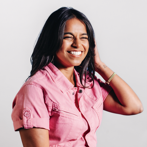 Sarah Corley, creator of Take Your Vitamins, smiling in a pink outfit for the wellness lifestyle brand's About page.