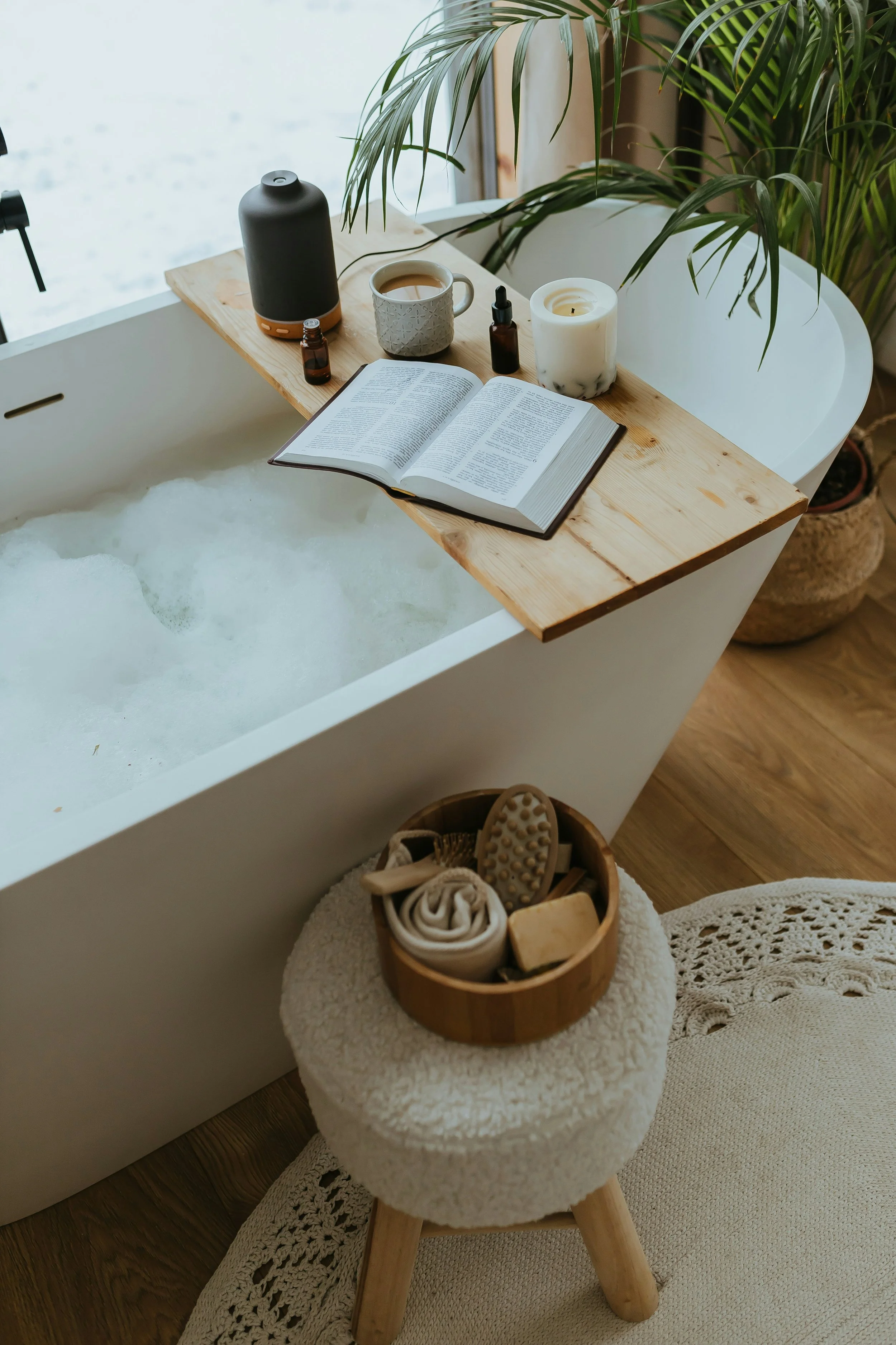 Cozy bath setup with candles, tea, essential oils, and a book for a relaxing wellness recovery routine.