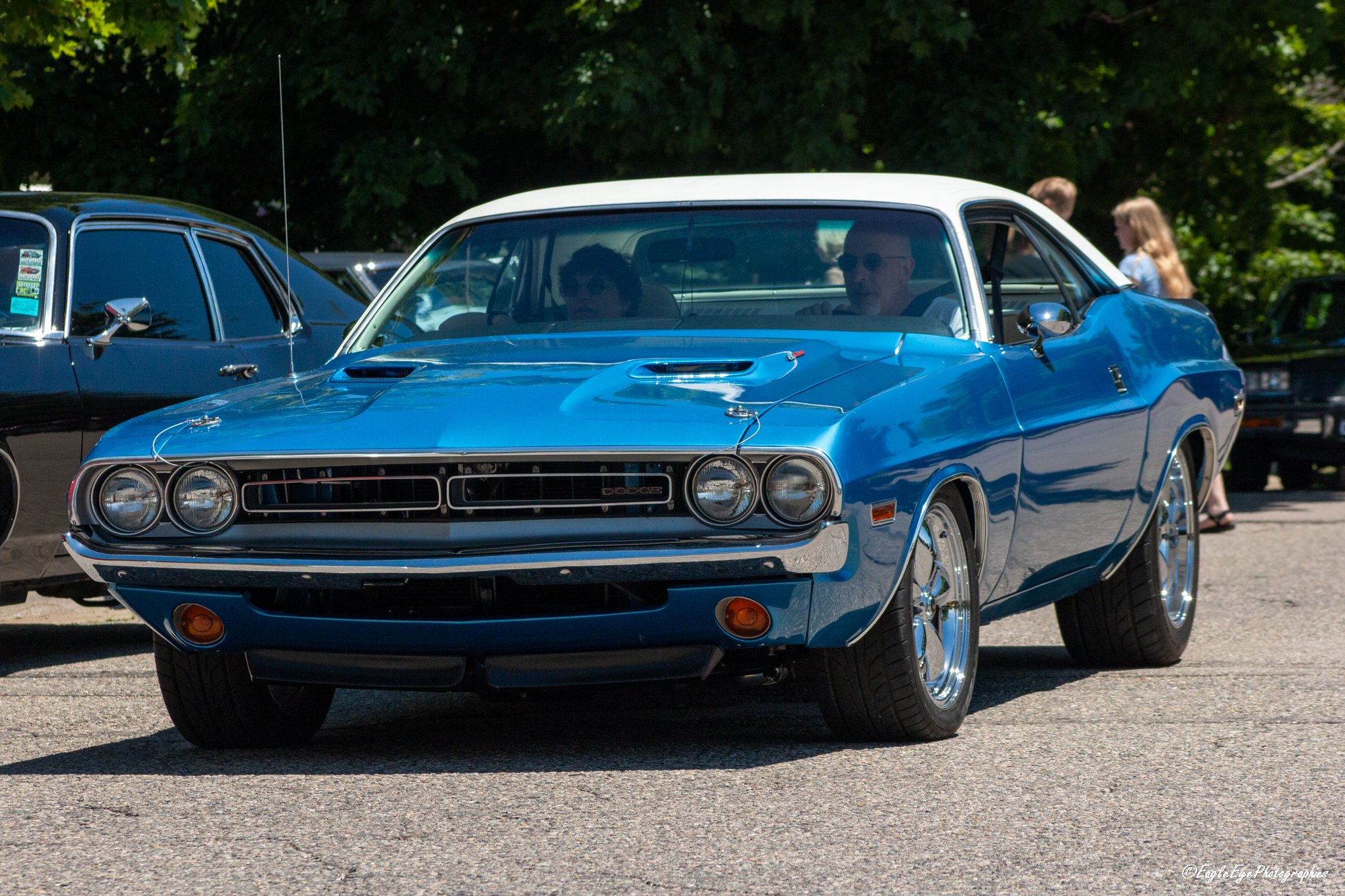 A vintage blue Dodge Challenger car at an outdoor car show with people in the background.
