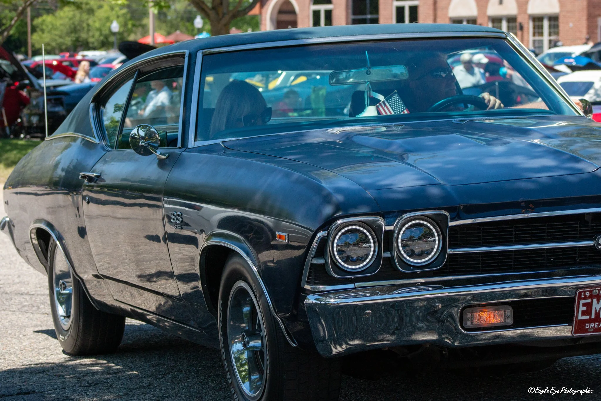 A vintage black Chevrolet car parked at a car show with other vehicles and people in the background.