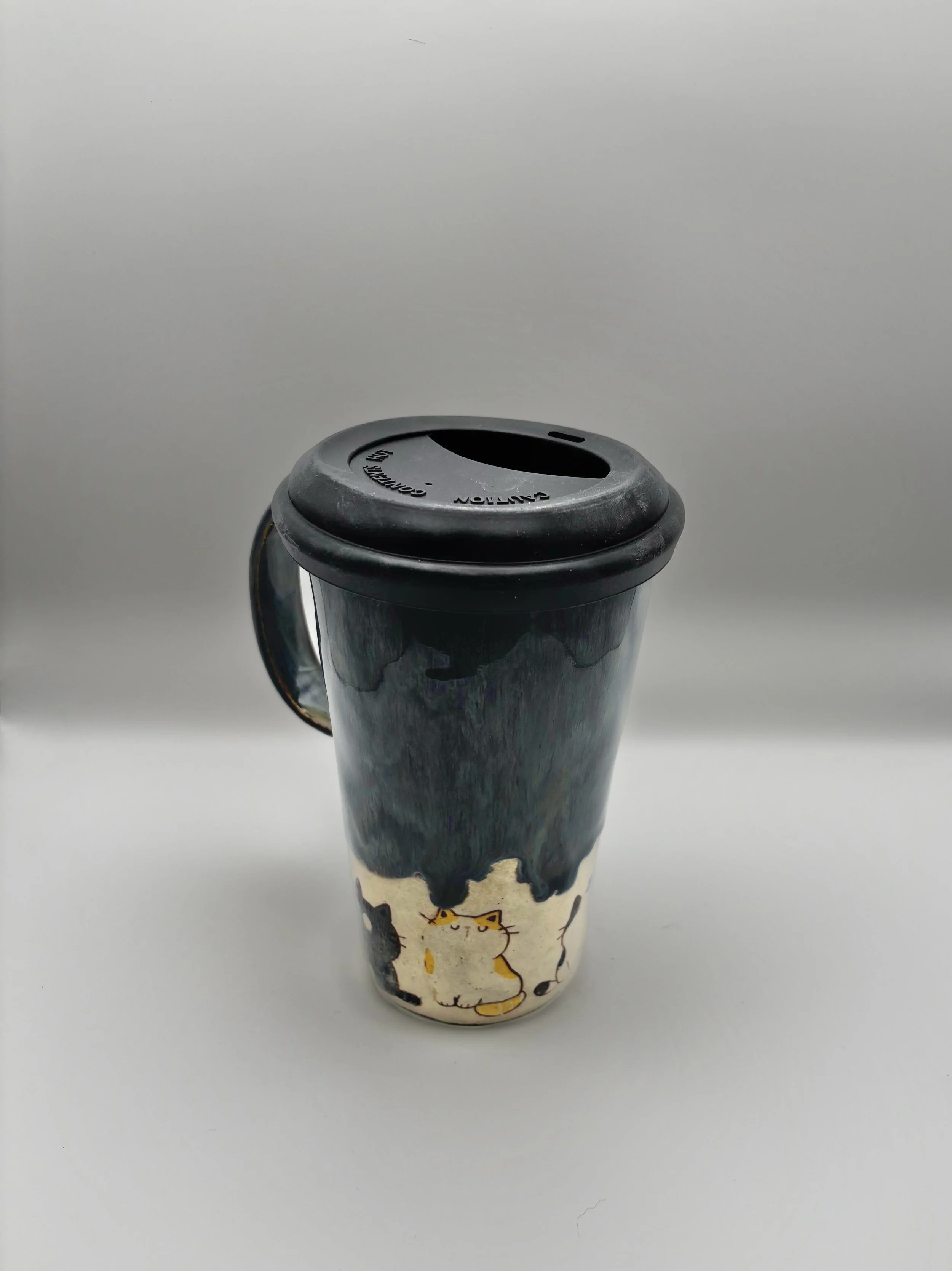 Handmade ceramic The Big Furbowski Travel mug with a cat illustration, with black spillproof lid, and gray, white, and black design.