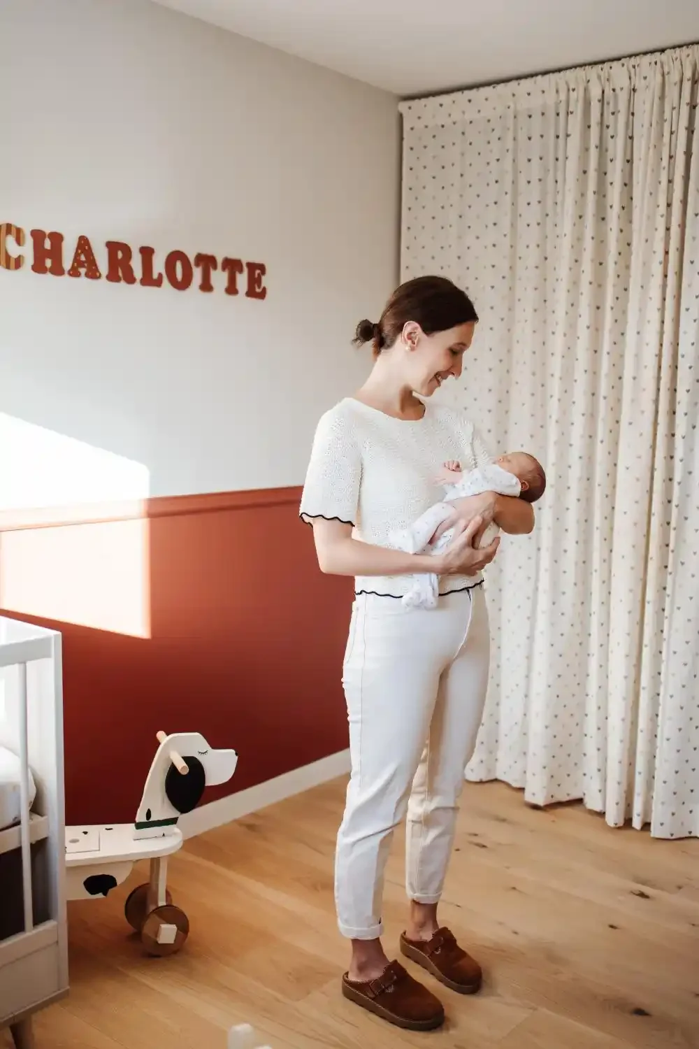 Maman debout dans la chambre, son nouveau-né contre elle, souvenir de naissance lifestyle à Villeneuve-d’Ascq