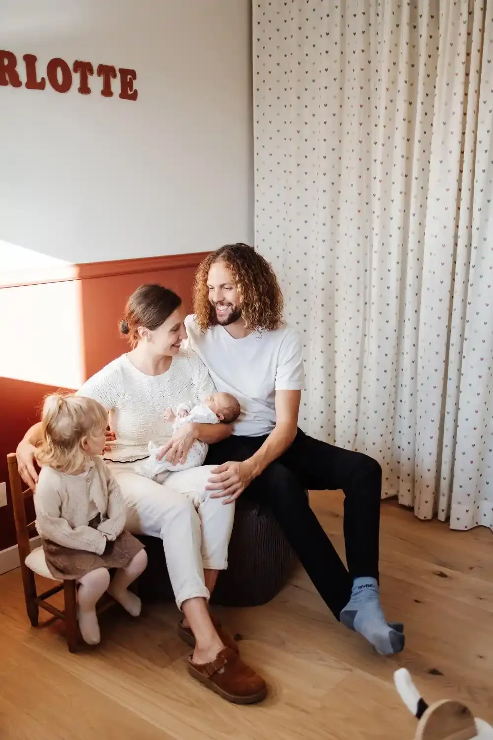 Famille réunie autour du nouveau-né dans la chambre de bébé, moment complice avec la grande sœur, séance photo famille à Villeneuve-d’Ascq