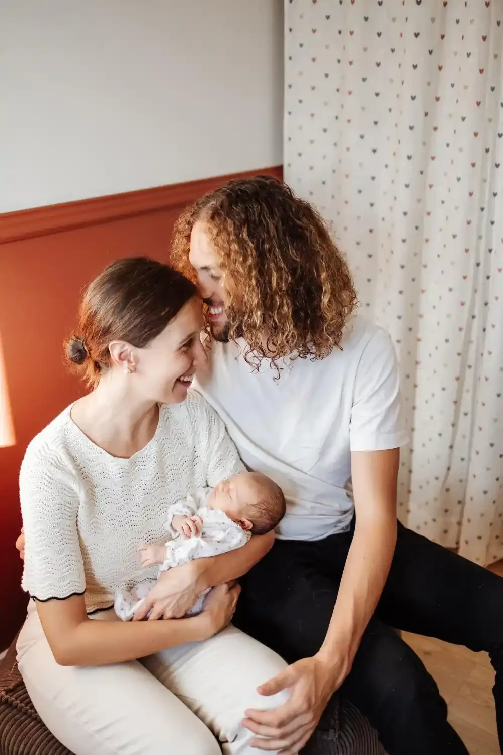 Les parents penchent la tête vers leur nouveau-né qu’ils tiennent contre eux, souvenir de naissance à domicile à Villeneuve-d’Ascq