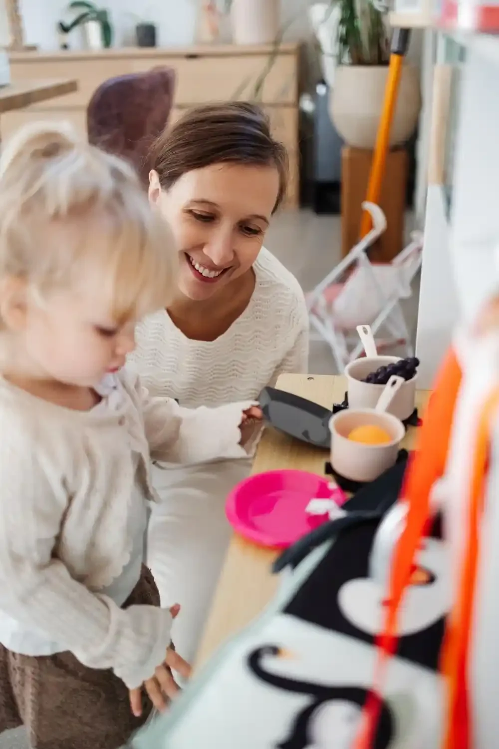 La grande sœur joue avec sa maman à la cuisine pendant la séance photo famille à domicile