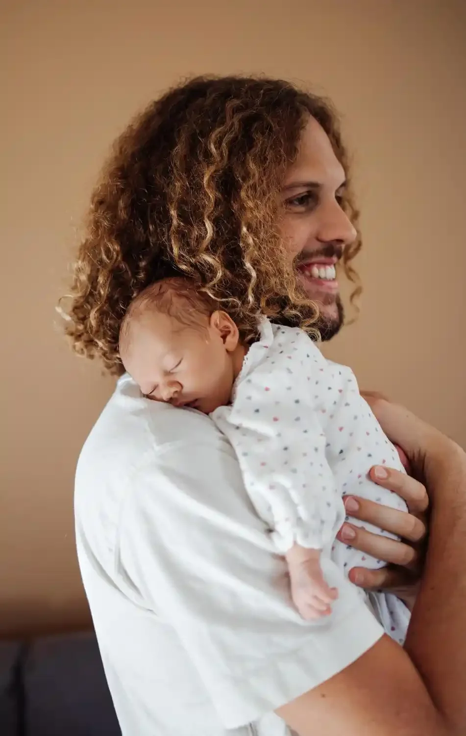 Papa souriant avec son nouveau-né endormi sur l’épaule, photo de naissance lifestyle à Villeneuve-d’Ascq
