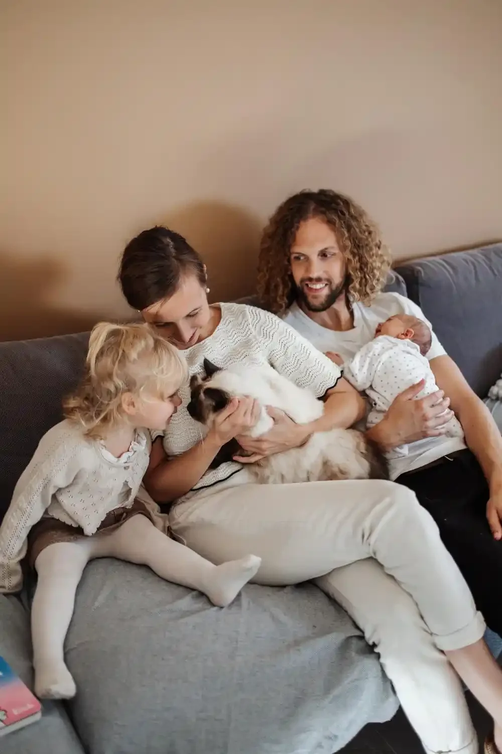 Famille de quatre sur le canapé : les parents, le nouveau-né et la grande sœur de 2 ans, photo de famille à domicile