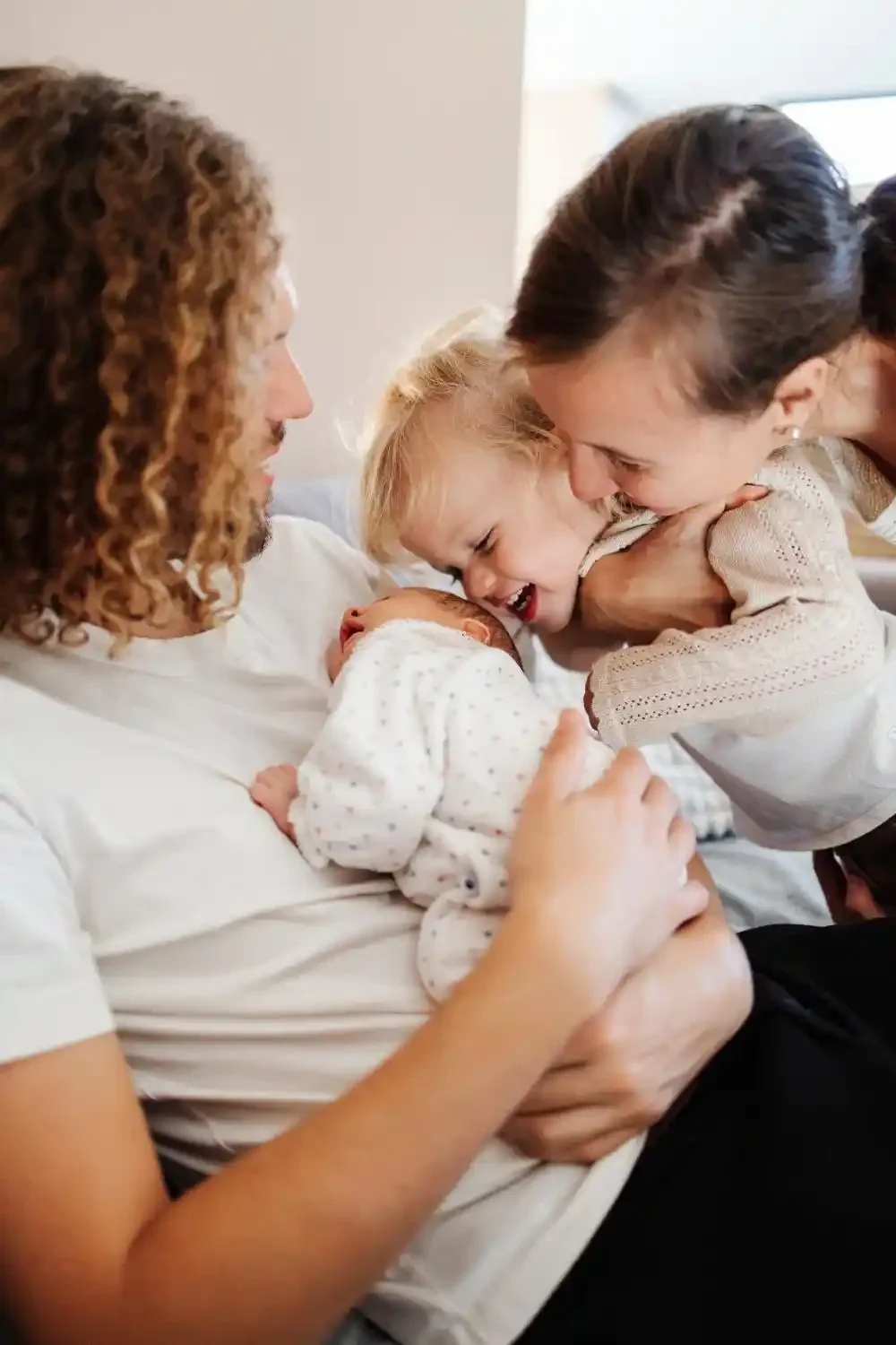 Gros plan sur les parents, le nouveau-né et la grande sœur blottis les uns contre les autres