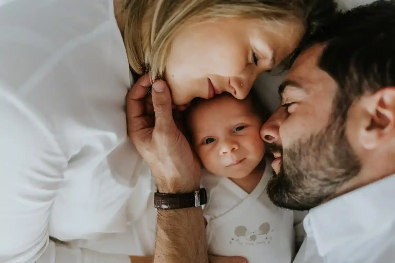 Photographe nouveau-né à domicile à Tournai, parents allongés avec leur bébé