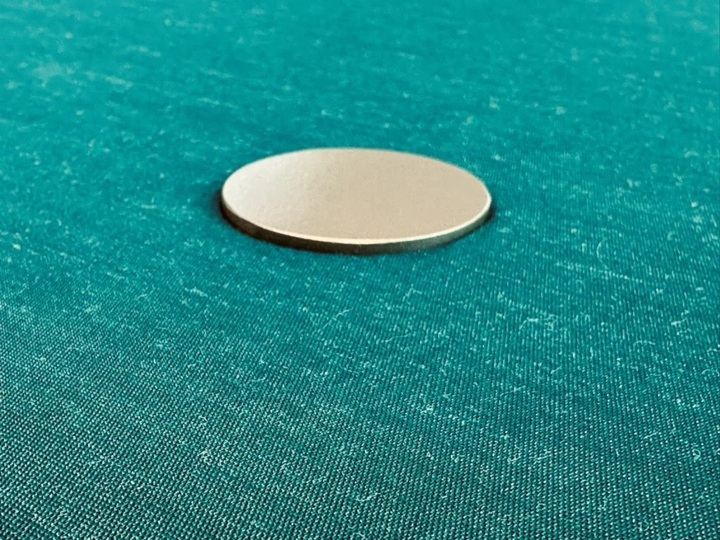 A silver-colored coin resting on a green poker table.