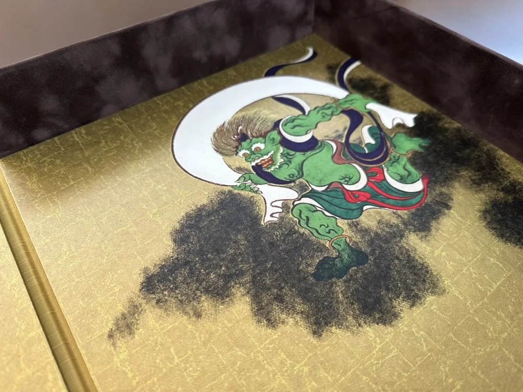 A traditional Asian painting featuring a green mythological creature with horns, sharp teeth, and a fierce expression, holding a sword and dressed in colorful garments, depicted on a gold background.