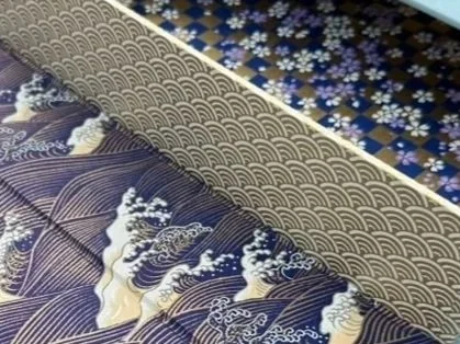 Close-up of a traditional Japanese fabric with wave and boat patterns, featuring blue, white, and beige colors.